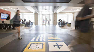 Students, blurred by motion, walk busily through the lobby of Crowe Hall.