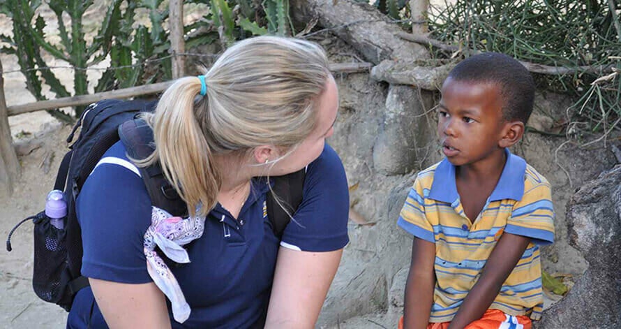 Student on service learning trip to Haiti talks with young student.