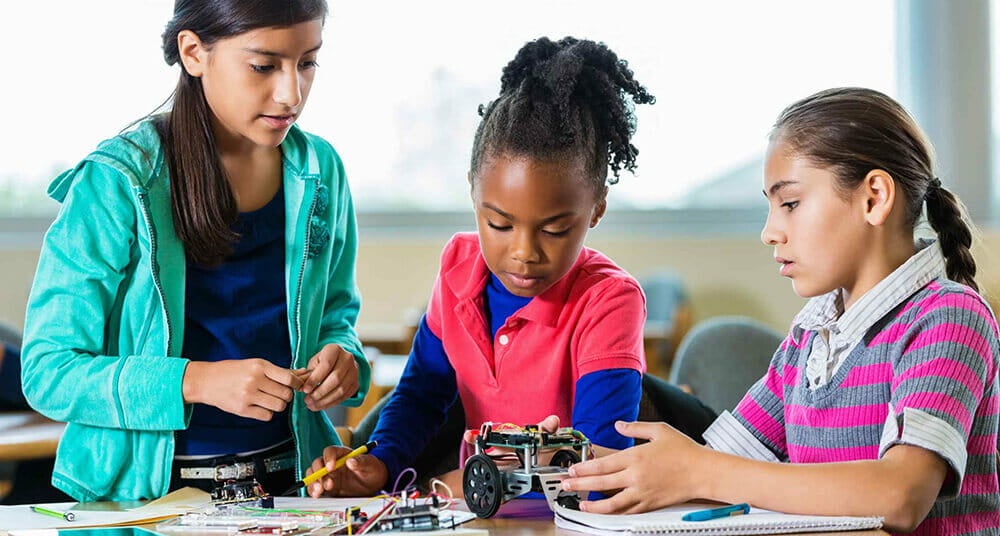 Elementary age Hispanic, African American, and Caucasian little girls are building a small robot