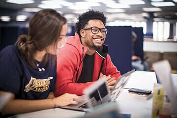 Two students in the library at a desk