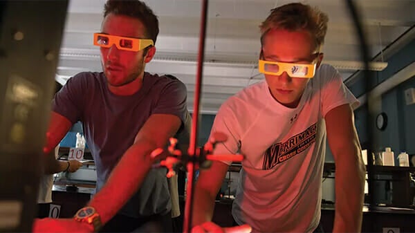 Two engineering students wearing eye shields conducting an experiment.