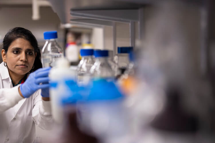 Dr. Leena Bharath examines a bottle in the lab.