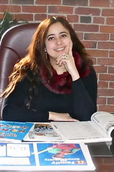 smiling person sitting at desk with open books