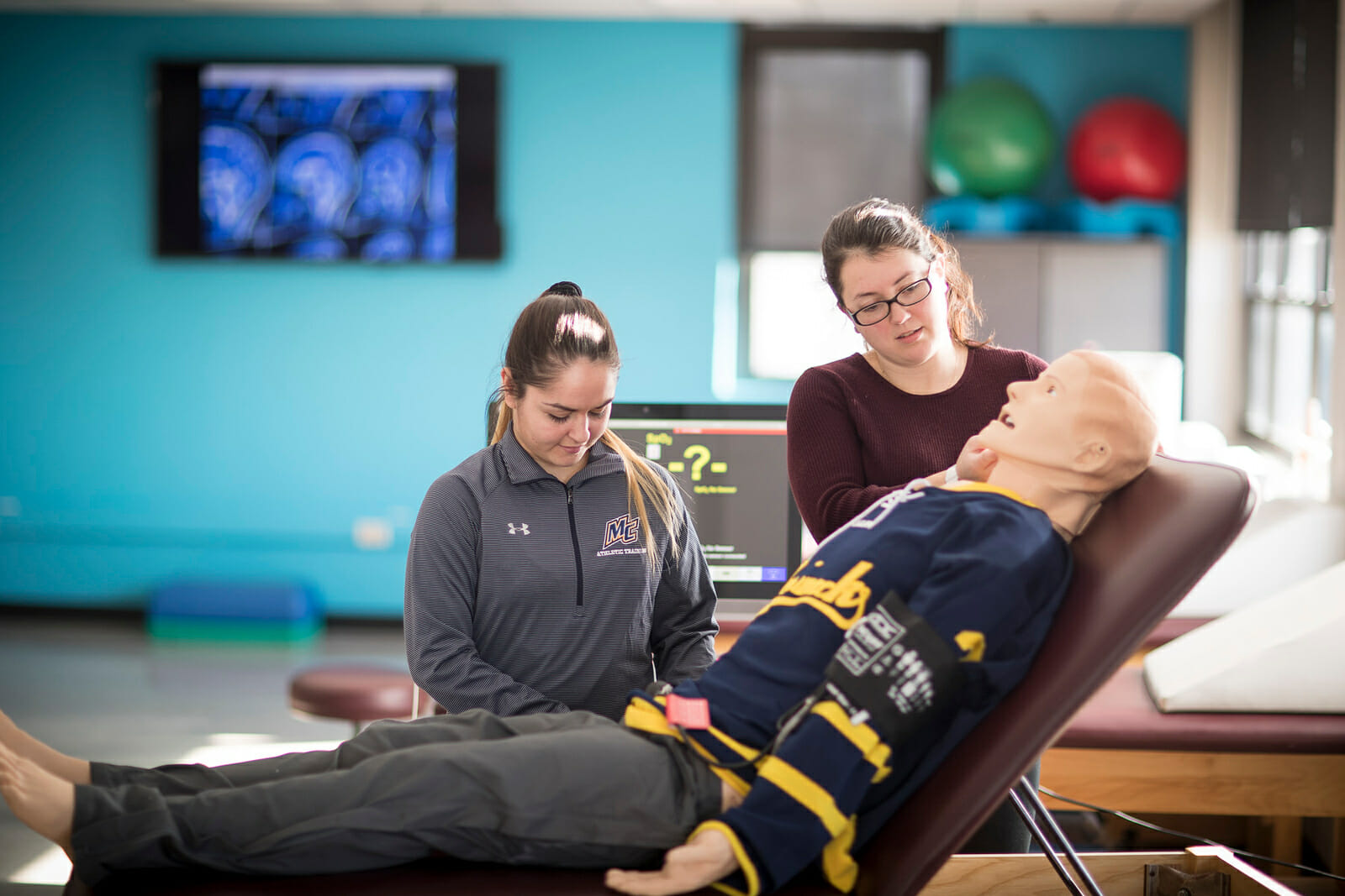 Athletic trainers with medical manikin on stretcher