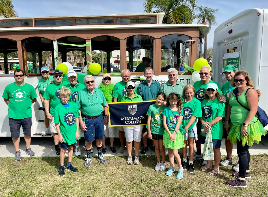 Alumni in green shirts stand in front of trolley