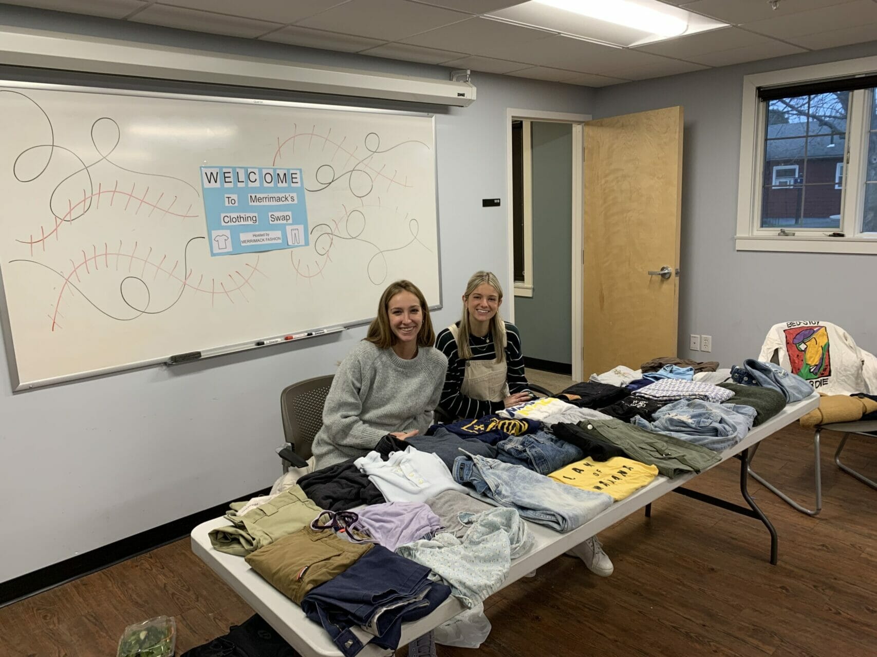 Brooklyn Stolgitis and Jessica McGee sit behind piles of donated clothes.