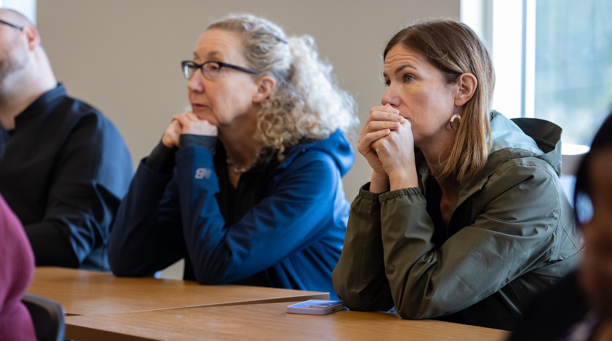 Two women sit attentively at a table during a discussion.