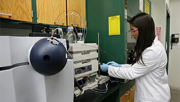 Student in a lab coat working in the Biology and Chemistry Department