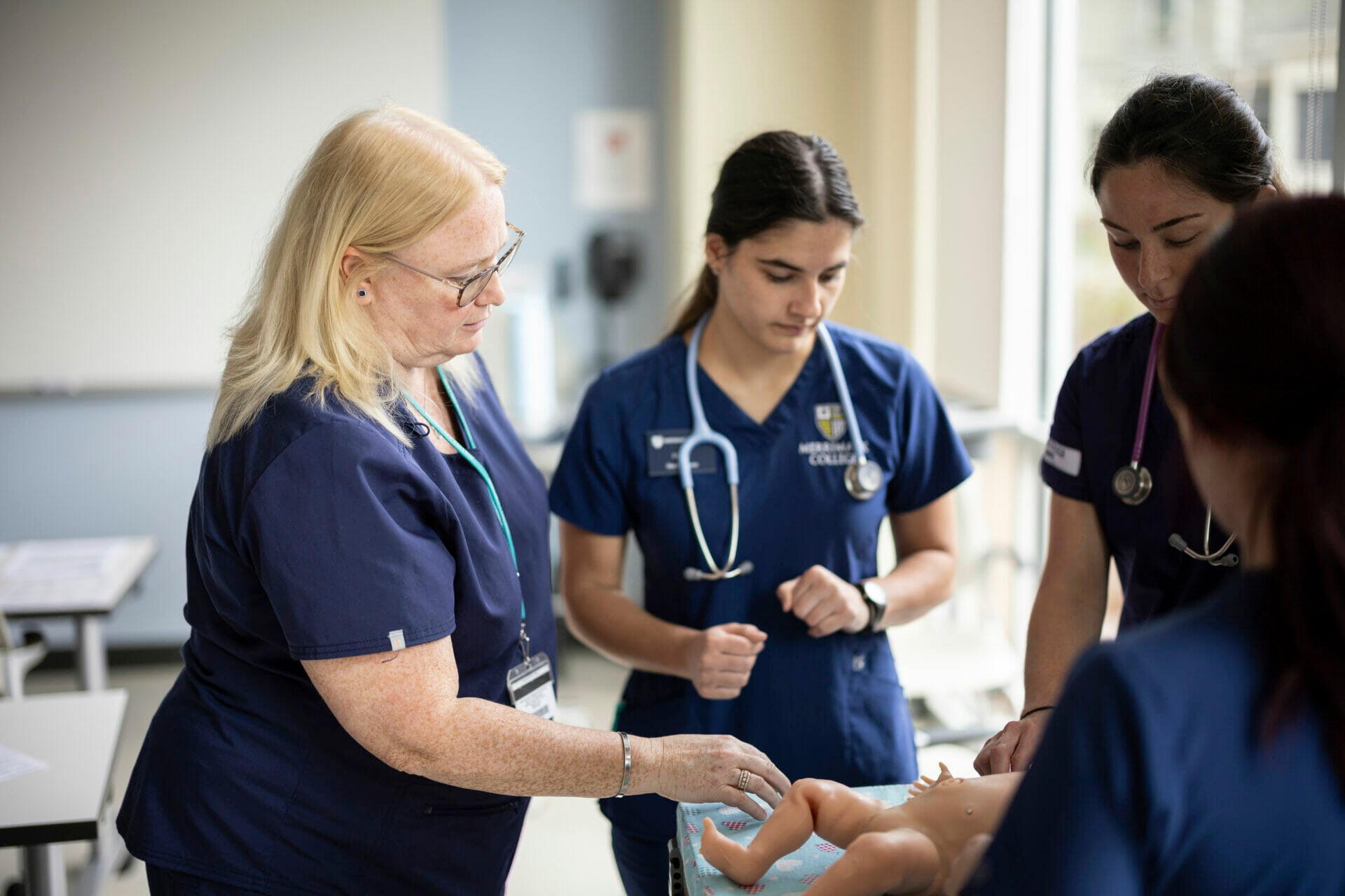 Nursing faculty and students examining baby manikin.