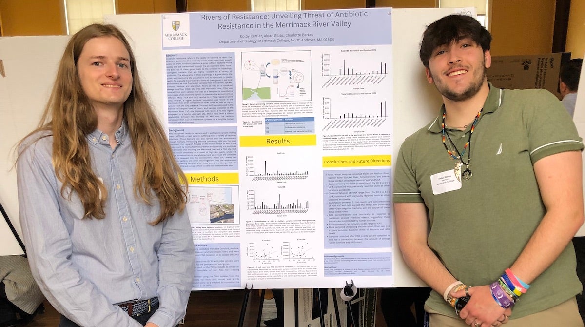 Photo Colby Currier M'24 of Aidan Gibbs '25 standing in front of a poster outlining their biology research.