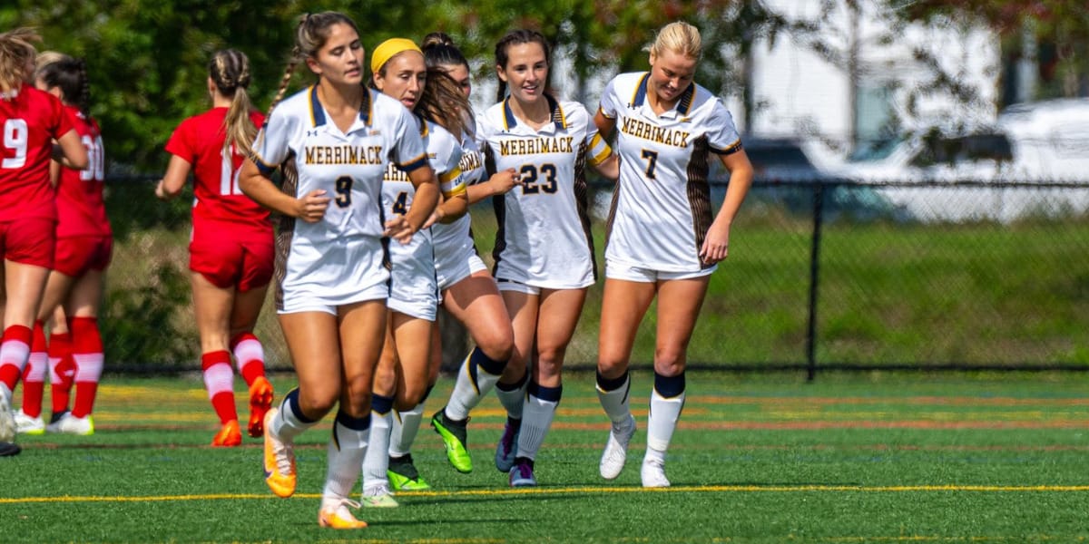 Photo of five Merrimack College Women's Soccer players running on a field.