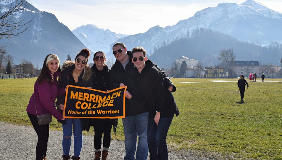 Students holding a Merrimack sign in front of mountains