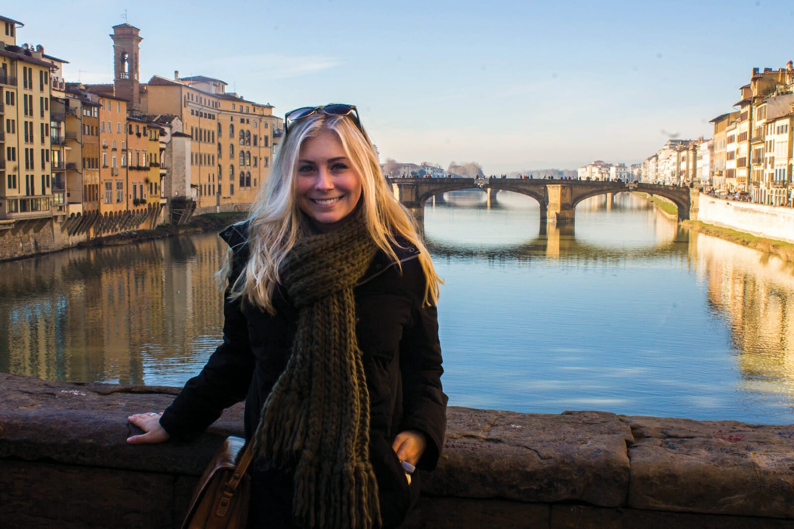 Student standing in front of water and bridges in Florence, Italy