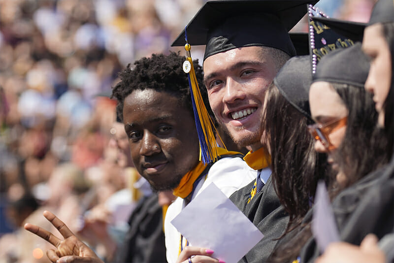 Students at Commencement smiling for camera.