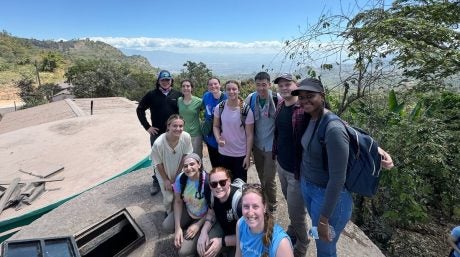 Group photo of Merrimack students and faculty posing in front of a cliff ridge in Honduras.