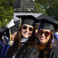 Photo of two smiling graduates at the Merrimack College 73rd Commencement exercises.