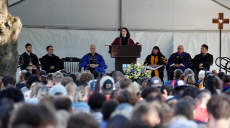 Photo of Laura Kurdziel speaking on stage in front of a crowd of students.
