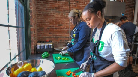 Two student volunteers chop vegetables in Hands to Help's new meal prep kitchen