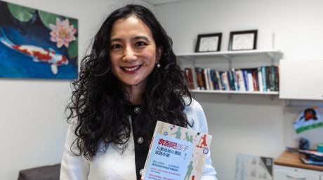 Photo of Zi Yan holding a copy of her book, “Run Kids: Exercise Physiology and Parents Practice Guide,”