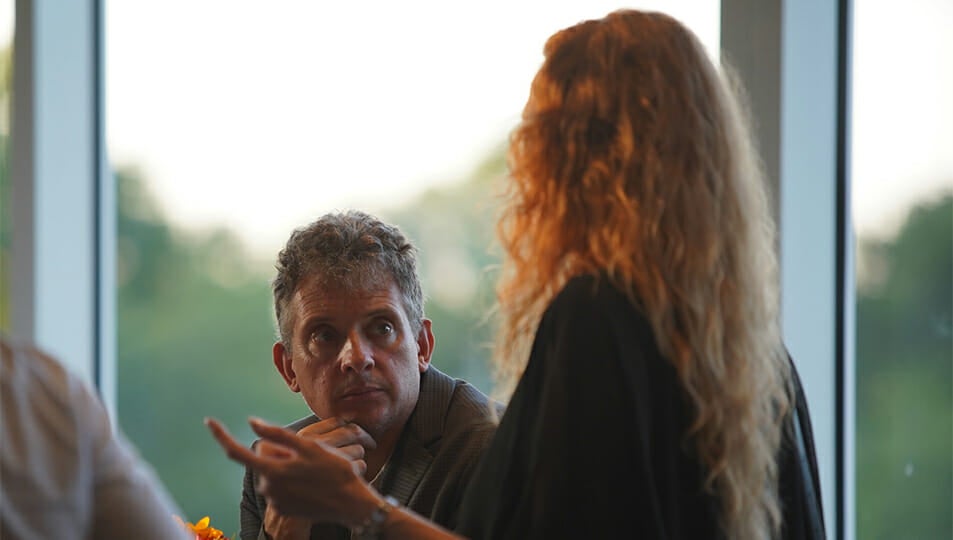Two faculty members talking in front of a window