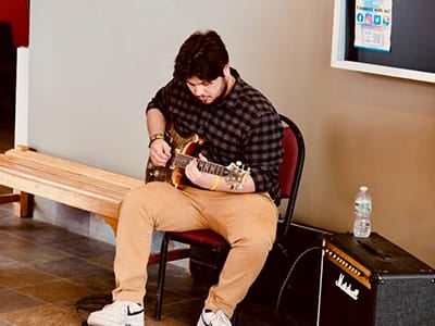 Drew Leuci playing guitar while seated